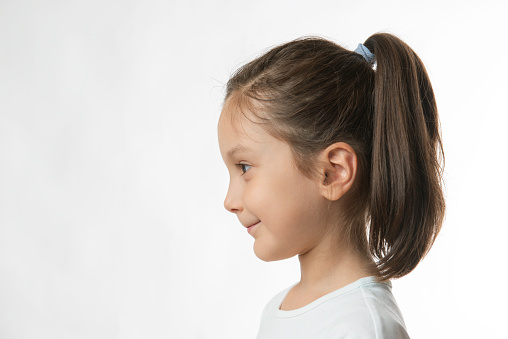 Portrait of a little girl with a cute smile in front of white background.