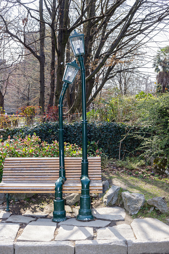 Turin, Italy - March 19, 2022: Bench in the Valentino Park with sculpture representing two lampposts in love.