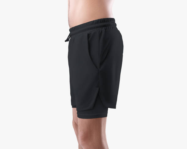 istock Mockup of black men's loose shorts with compression lining, training undershorts on a man's athletic body, isolated on background. 1392083084