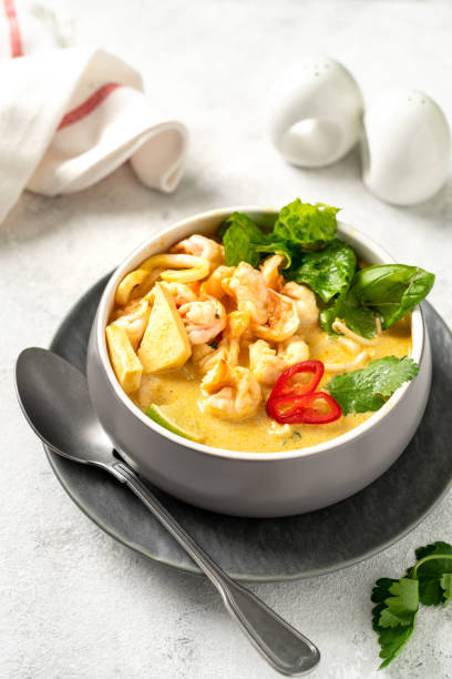 istock Asian laksa soup with shrimp in a ceramic bowl on a light culinary background. Spicy broth soup with coconut milk, rice noodles and seafood in a plate on the closeup kitchen table closeup 1392085645