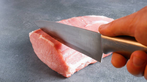 istock Raw meat. The chef cuts an appetizing cue ball with a knife on a gray background. 1392086537