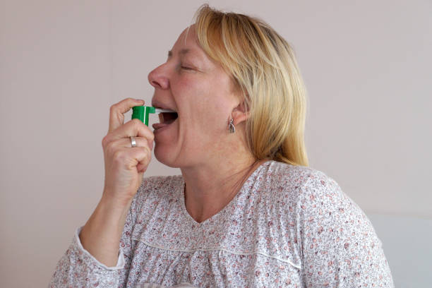 istock woman spraying medicinal spray on her sore throat 1392086608