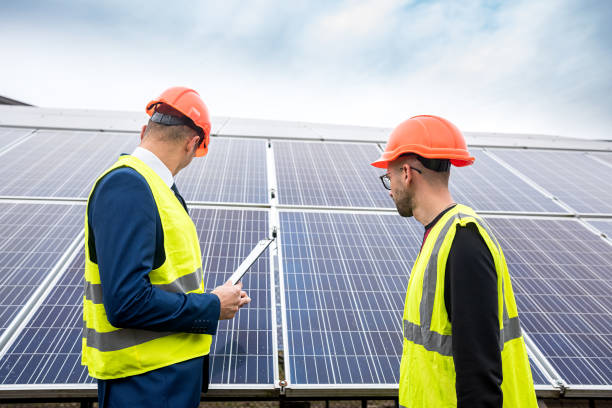 istock tall men in work clothes are considering whether to install solar panels in the open air. 1392086871