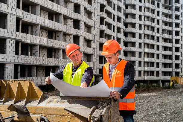 istock wonderful male workers in uniform and with helmets consider a construction plan on a grader 1392086886