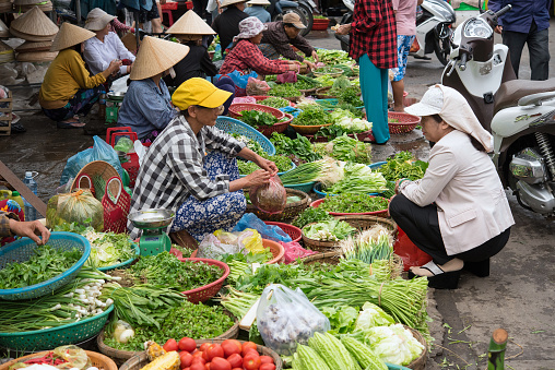 Woman buying fresh organic green vegetables at the village bazaar market in Asia.