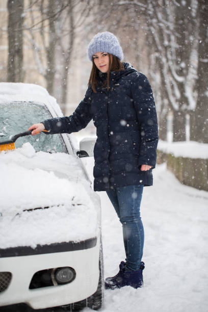 ある女性が車のフロントガラスから雪を降らせます。 - snow car window ice scraper ストックフォトと画像