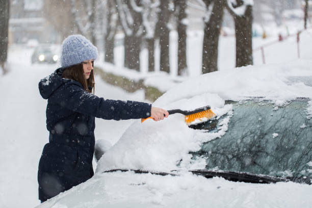 ある女性が車のフロントガラ��スから雪を降らせます。 - snow car window ice scraper ストックフォトと画像