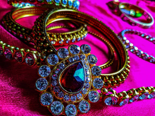 Stock photo of beautiful diamond waist belt,water drop shape brooch decorated with small white diamond, dark pink color diamond in the the middle of the brooch.waist belt kept on pink color background foto de archivo del hermoso cinturón de cintura de diamante, broche en forma de gota de agua decorado con un pequeño diamante blanco, diamante de color rosa oscuro en el medio del broche.cinturón de cintura mantenido en fondo de color rosa