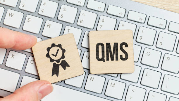 Acronym QMS or Quality Management System. Text with an icon on a piece of wood on the keyboard stock photo