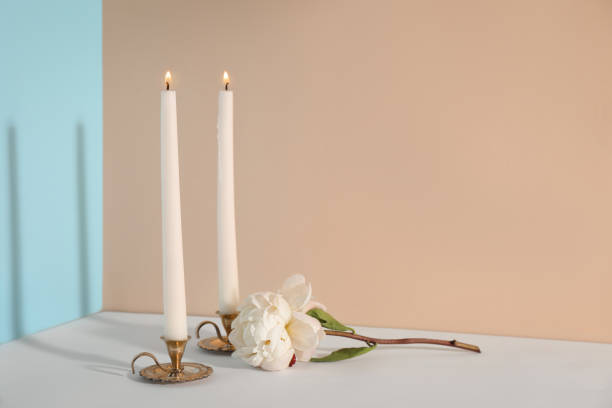 istock Elegant candlesticks with burning candles and flower on white table 1392090896