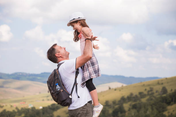 istock Man with backpack picking his silly daughter up and smiling 1392091824