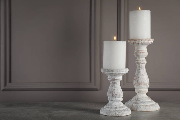 istock Elegant candlesticks with burning candles on grey table. Space for text 1392091834