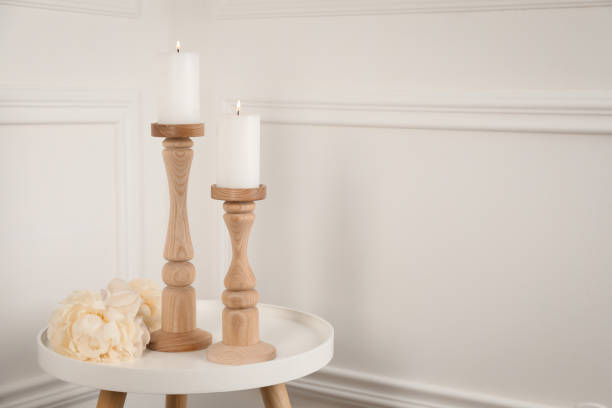 Elegant candlesticks with burning candles and flower on white table. Space for text