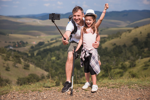 Father and daughter having a great time on a hike and taking a stop to make a selfie