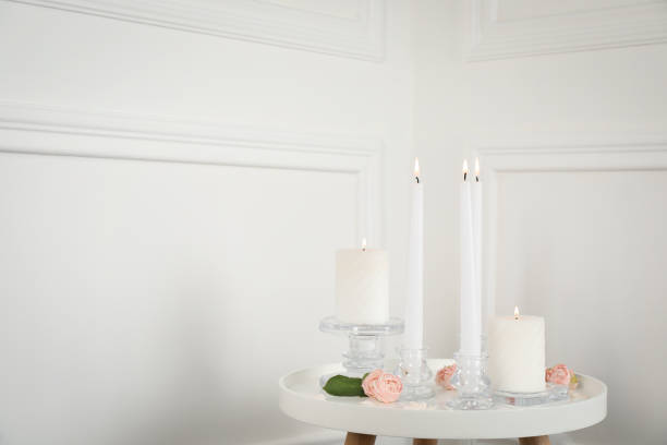 istock Elegant candlesticks with burning candles and flowers on white table. Space for text 1392092130