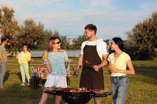 Group of friends cooking food on barbecue grill in park