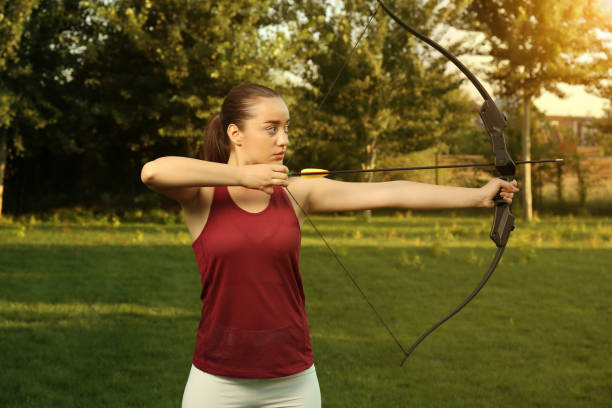 istock Woman with bow and arrow practicing archery in park 1392092290