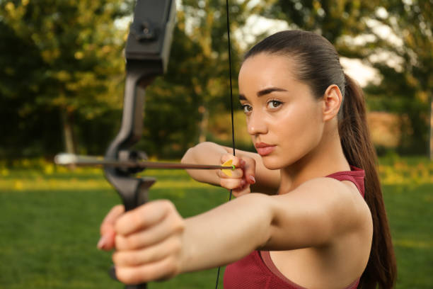 Woman with bow and arrow practicing archery in park