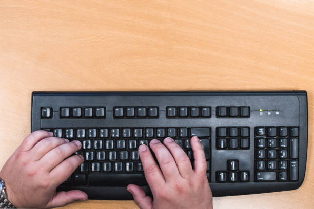 istock male hands on a black keyboard, isolated on brown 1392093014