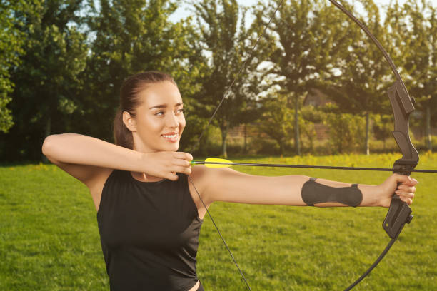 istock Woman with bow and arrow practicing archery in park 1392093236