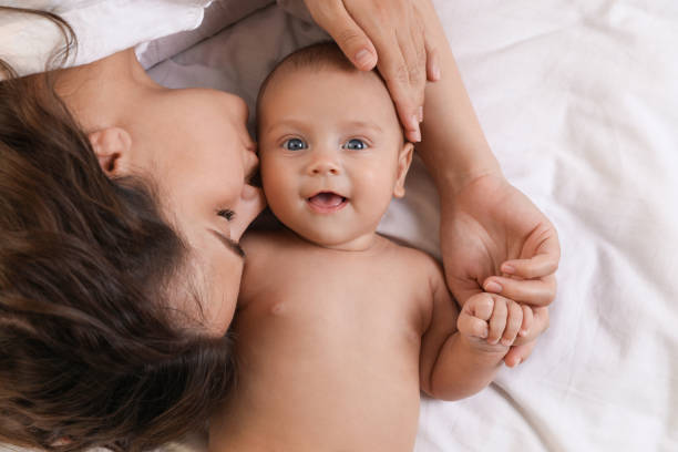 istock Young mother with her cute baby on bed, top view 1392093375