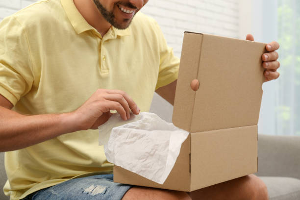istock Happy man opening parcel on sofa at home, closeup. Internet shopping 1392094121