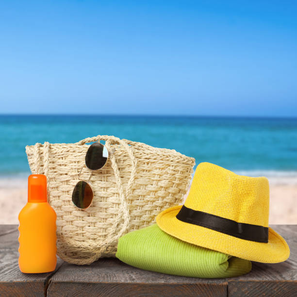 istock Stylish bag with beach accessories on wooden surface near seashore 1392094540