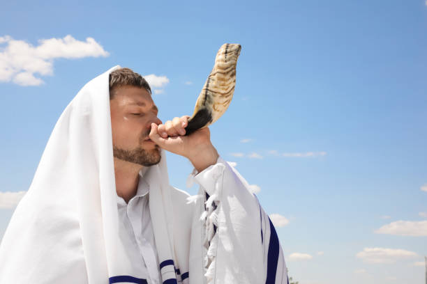 istock Jewish man in tallit blowing shofar outdoors. Rosh Hashanah celebration 1392094893
