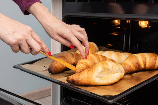 istock woman flipping a croissant lying on a baking sheet 1392096081