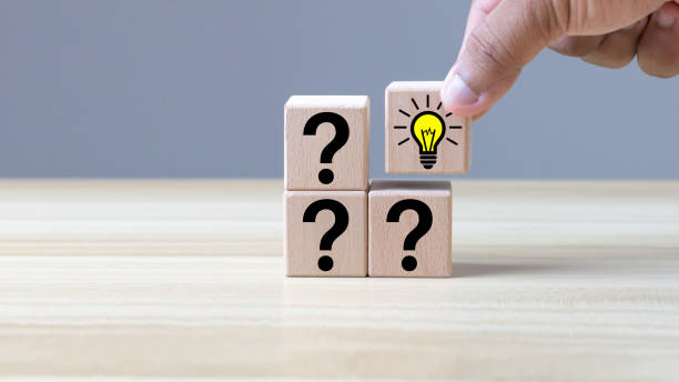 istock Concepts and creativity. Male hand holding wooden cube block with question symbol and light bulb icon. copy space 1392097621
