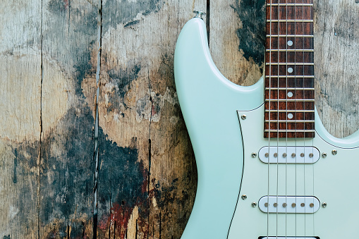 Detail of Mint Green Electric Guitar on a wood background.