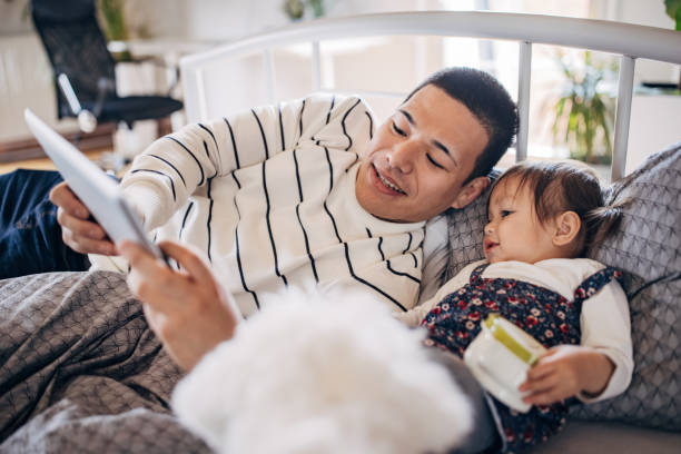 istock Father and daughter lying on the bed and looking something on digital tablet 1392101458