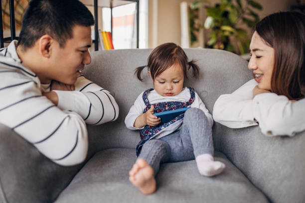 istock Mother and father looking at their daughter while she is using smart phone on the sofa 1392103970