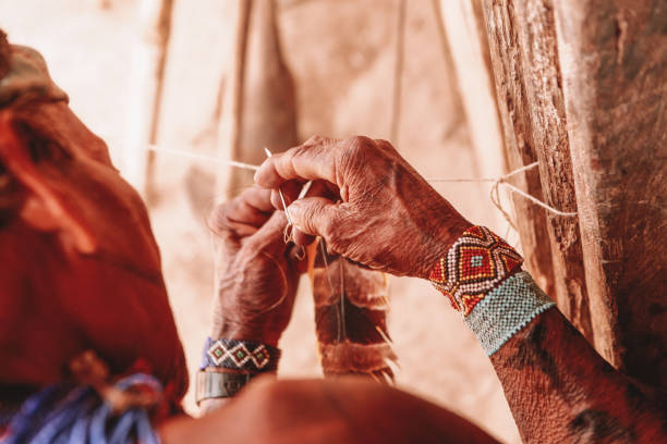 indigenous person making a feather headdress - tribal art fotos imagens e fotografias de stock