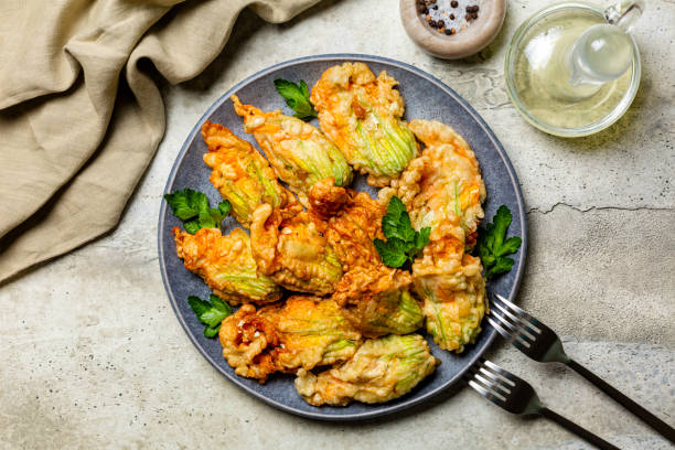 aperitivo italiano. frito en una masa de flores de calabacín rellenas de queso ricota y perejil. flor de calabacín o calabaza asada. fiori di zucca in pastella. fondo de piedra. - squash blossom fotografías e imágenes de stock