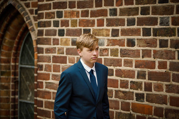 Lutheran Protestant Communion. Portrait of teenager in his confirmation suit. Fourteen year old boy standing in front of the church