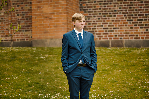 Lutheran Protestant Communion. Portrait of teenager in his confirmation suit. Fourteen year old boy standing in front of the church