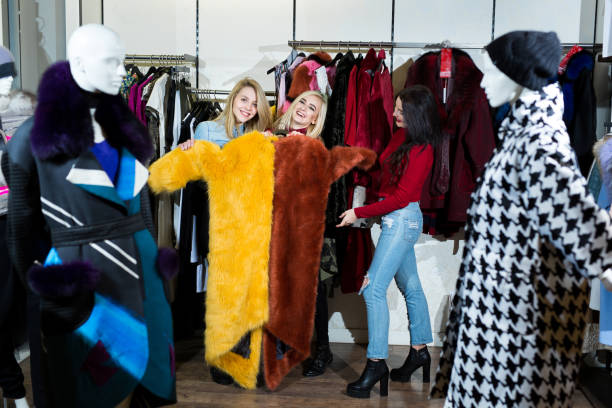 istock Three women trying on a fur coat in the store. 1392110967