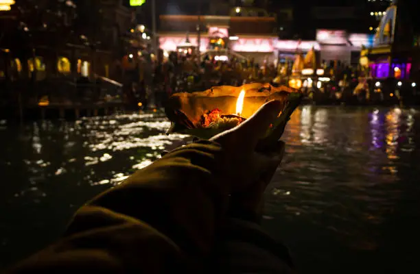 devotee holding aarti flower pot for ganges river evening prayer at night