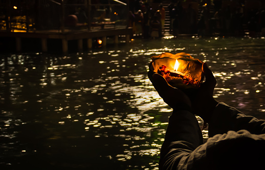 devotee holding aarti flower pot for ganges river evening prayer at night