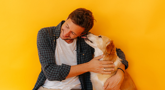 Portrait of a dog and young man, his owner - kissing and licking