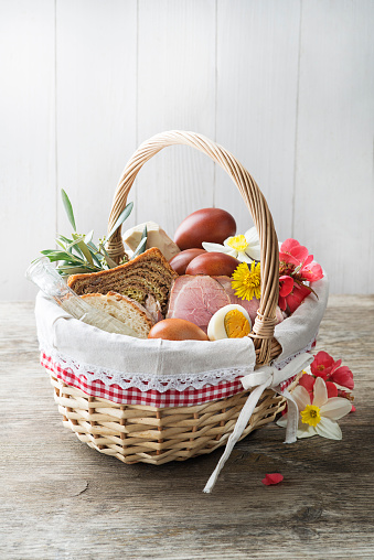 Easter traditional food with ham, eggs and bread in basket. Holidays background. Easter basket filled with all sorts of delicious delicatessen ready for an Easter meal.