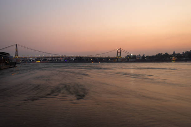 puente colgante de hierro con cielo dramático al atardecer y agua borrosa del río por la noche - photography suspension bridge water night fotografías e imágenes de stock