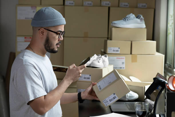istock Asian male small business owner using mobile app on smartphone checking parcel box. 1392117075