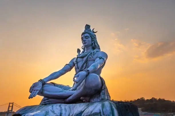 hindu god lord shiva statue in meditation posture with dramatic sky at evening from unique angle image is taken at parmarth niketan rishikesh uttrakhand india on Mar 15 2022.