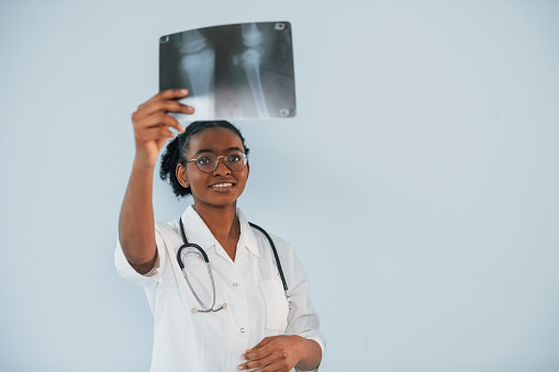 Holding x-ray. Young african american woman is against white background.