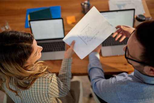 High angle view of business couple talking while working on reports in the office.