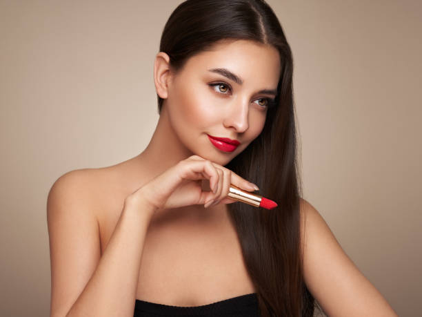 istock A beautiful young woman applying lipstick 1392121271