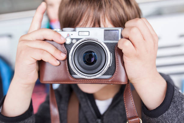 Child boy taking pictures with retro camera. He is about to press the shutter