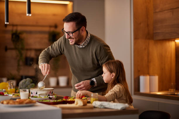 istock Happy single father and daughter cooking lunch in the kitchen. 1392122804